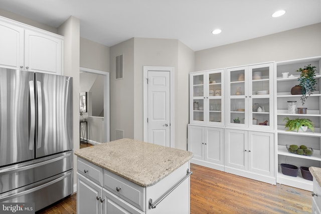 kitchen featuring white cabinets, a center island, hardwood / wood-style floors, and stainless steel fridge