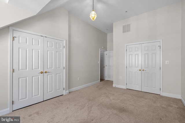 unfurnished bedroom with high vaulted ceiling and light colored carpet