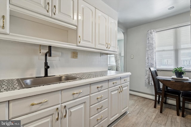 kitchen with backsplash, sink, light hardwood / wood-style flooring, and white cabinets