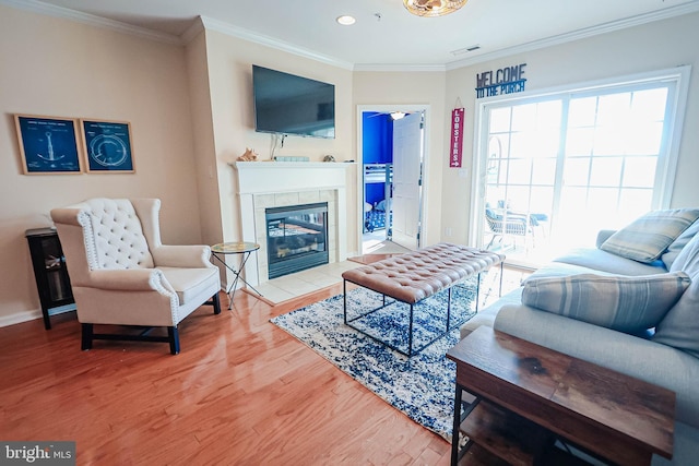 living room with hardwood / wood-style flooring, crown molding, and a tile fireplace