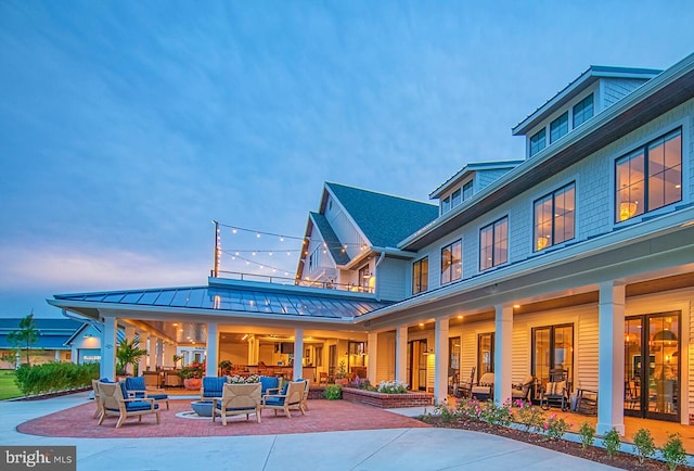 back house at dusk with an outdoor living space and a patio