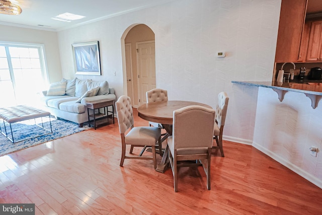 dining space with crown molding and light hardwood / wood-style floors