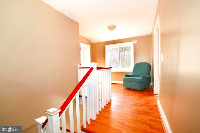 corridor with hardwood / wood-style floors and vaulted ceiling