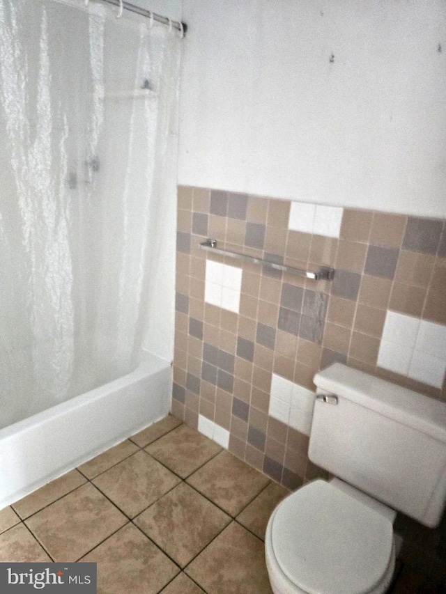 bathroom with tile patterned flooring, shower / bath combo, tile walls, and toilet