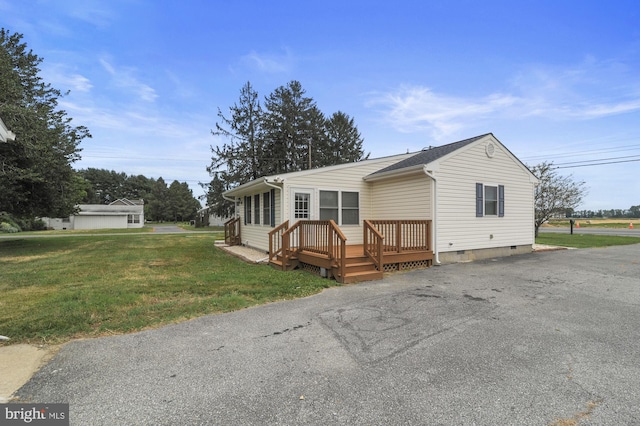 view of front facade with a wooden deck and a front yard