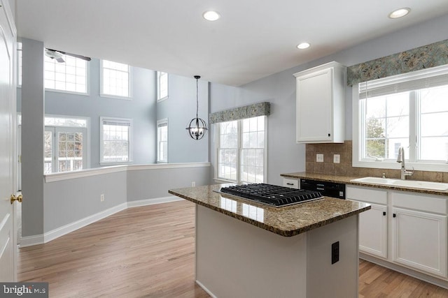 kitchen featuring sink, white cabinetry, dark stone counters, a center island, and light hardwood / wood-style floors