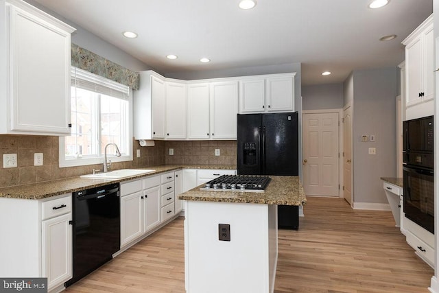 kitchen with a kitchen island, black appliances, white cabinets, and sink