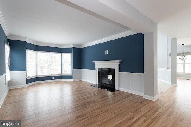 unfurnished living room with light hardwood / wood-style flooring, crown molding, and a chandelier