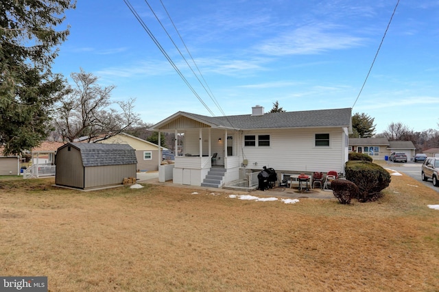 view of front of house featuring a porch, a patio area, a front lawn, and a storage shed