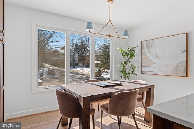 dining space with light hardwood / wood-style floors and a chandelier