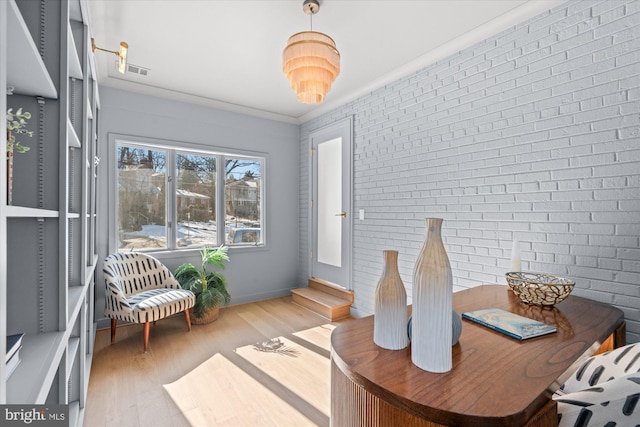 interior space with crown molding, hardwood / wood-style flooring, and brick wall