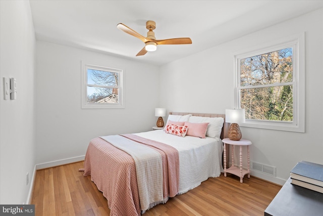 bedroom with ceiling fan, multiple windows, and light hardwood / wood-style flooring