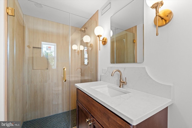 bathroom featuring a shower with door and vanity