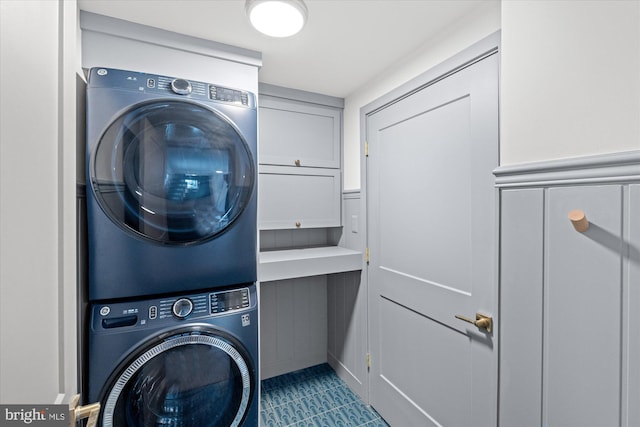 laundry room with cabinets and stacked washer and dryer