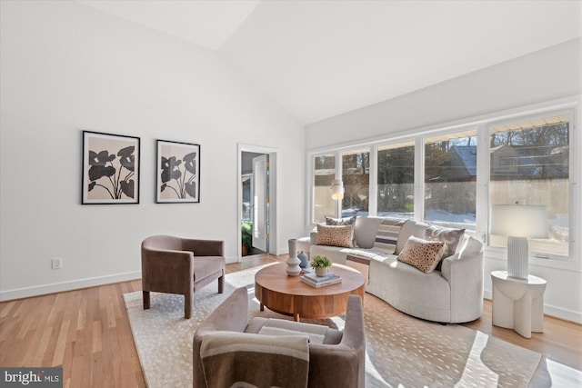 living room with high vaulted ceiling and light wood-type flooring