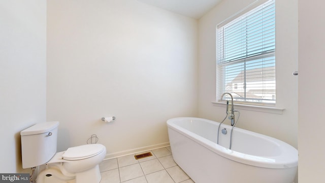 bathroom with a washtub, tile patterned floors, and toilet