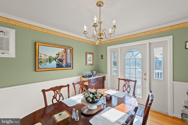 dining area with an inviting chandelier, ornamental molding, and light wood-type flooring