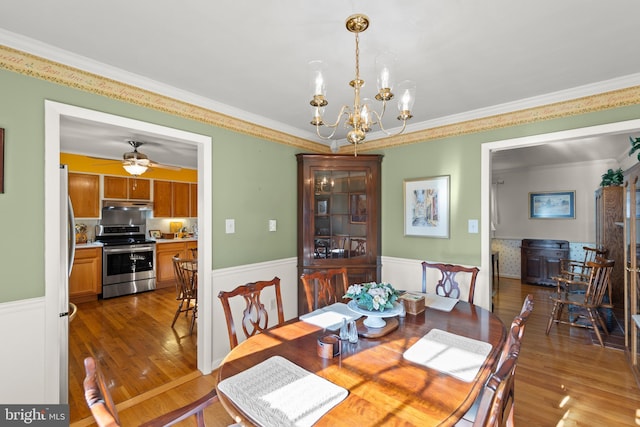 dining area featuring wood-type flooring, ornamental molding, and ceiling fan with notable chandelier