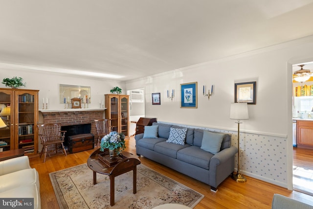 living room with crown molding, a wall mounted AC, a brick fireplace, and light wood-type flooring