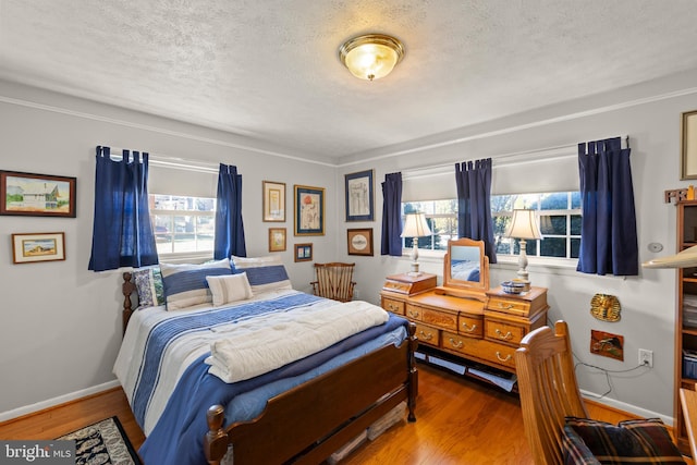 bedroom with multiple windows, hardwood / wood-style flooring, and a textured ceiling