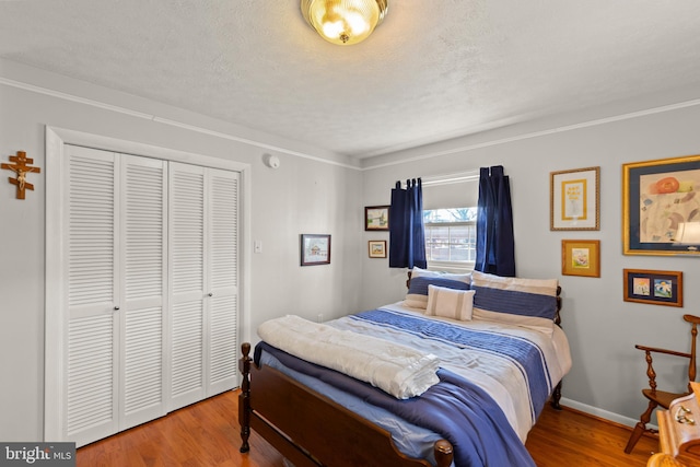 bedroom featuring ornamental molding, hardwood / wood-style floors, a textured ceiling, and a closet