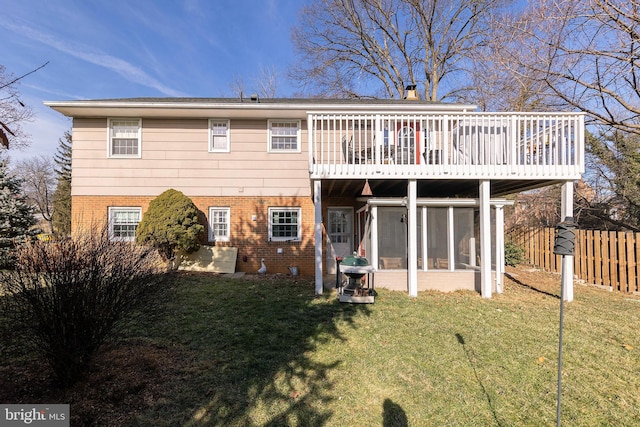 back of property featuring a yard, a sunroom, and a deck