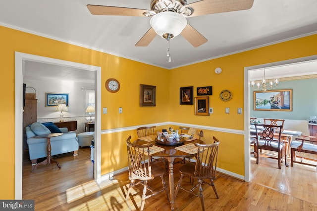 dining room with crown molding, ceiling fan with notable chandelier, and light hardwood / wood-style flooring