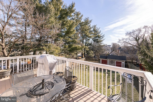 wooden deck with a grill, a lawn, and a storage shed