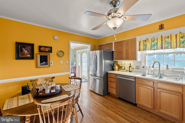 kitchen with ceiling fan, appliances with stainless steel finishes, sink, and light hardwood / wood-style flooring