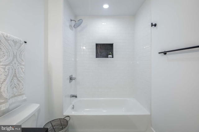 bathroom with toilet and tiled shower / bath combo