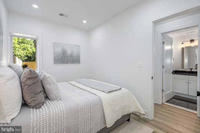 bedroom featuring sink, light hardwood / wood-style floors, and connected bathroom