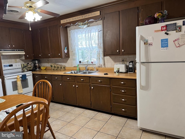 kitchen featuring light tile patterned floors, sink, white appliances, and dark brown cabinetry