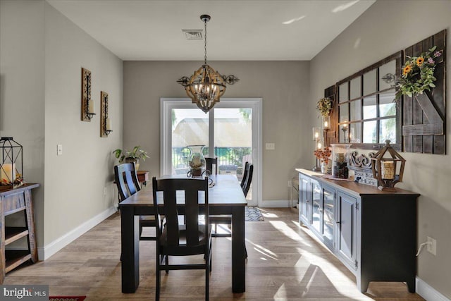 dining space with an inviting chandelier and light hardwood / wood-style flooring