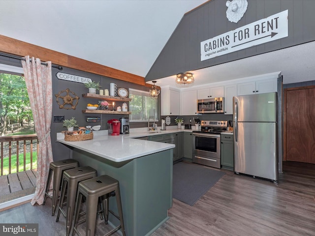 kitchen featuring sink, decorative light fixtures, kitchen peninsula, stainless steel appliances, and white cabinets