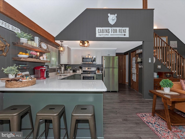 kitchen featuring sink, white cabinetry, stainless steel appliances, dark hardwood / wood-style flooring, and kitchen peninsula