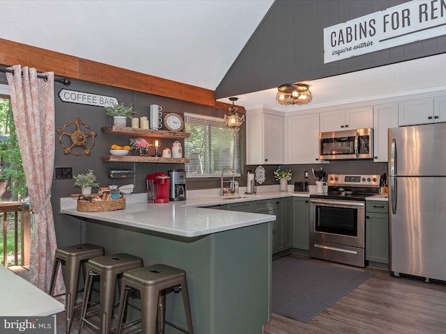 kitchen featuring sink, wood-type flooring, hanging light fixtures, kitchen peninsula, and stainless steel appliances