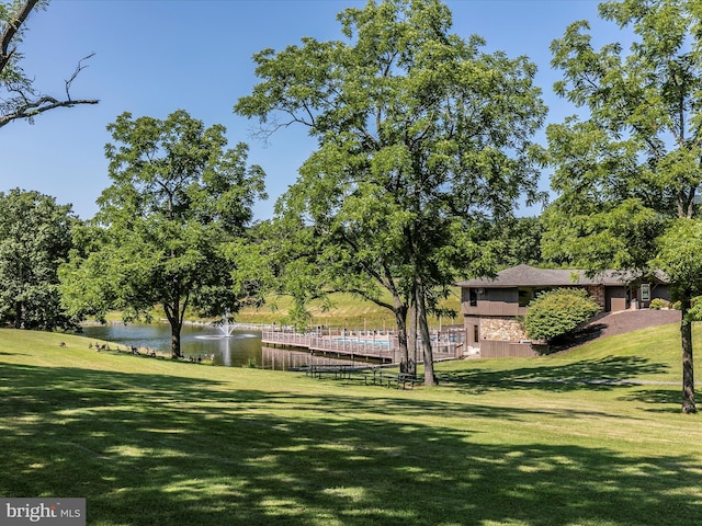 view of property's community with a water view and a lawn