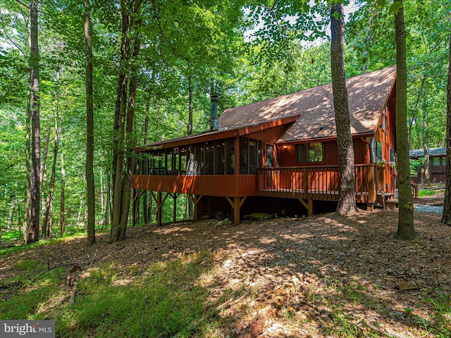 rear view of property with a sunroom and a deck