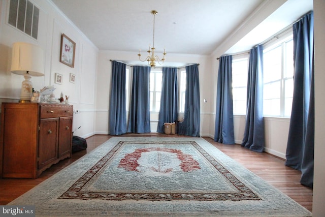 living area with hardwood / wood-style flooring, crown molding, and a notable chandelier