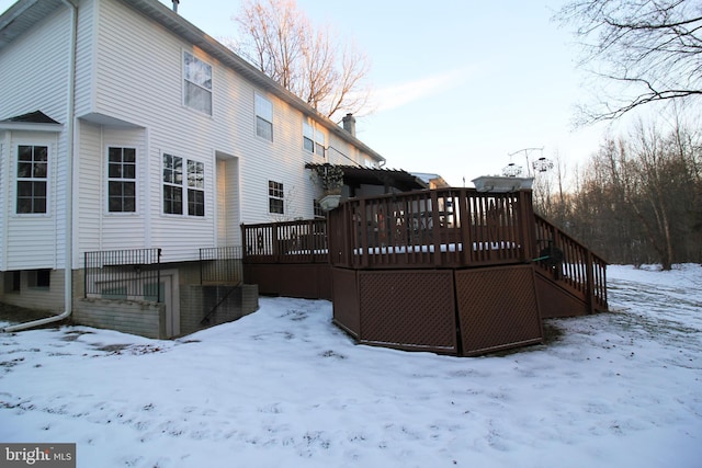 snow covered rear of property with a wooden deck