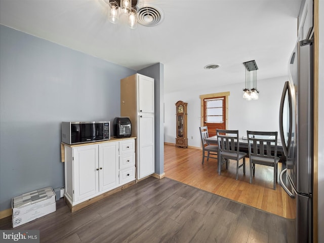 kitchen featuring decorative light fixtures, white cabinets, dark hardwood / wood-style floors, a chandelier, and stainless steel refrigerator