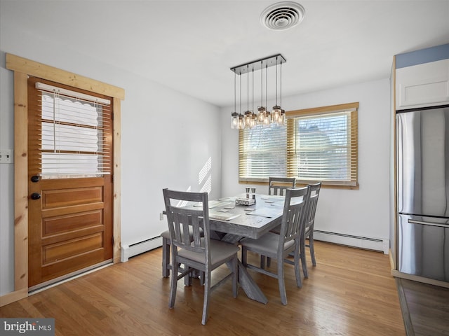 dining area featuring a baseboard radiator and light hardwood / wood-style flooring