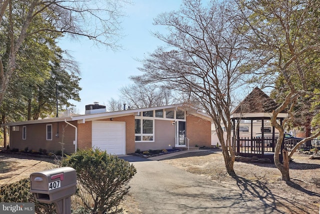 view of front of home featuring a garage, driveway, brick siding, and a chimney