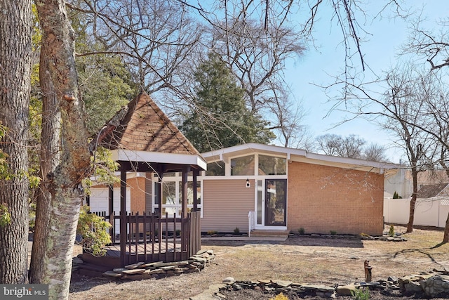 back of house with brick siding and fence