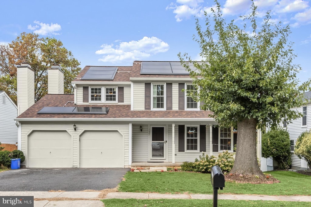 view of front facade with a garage, a front yard, covered porch, and solar panels