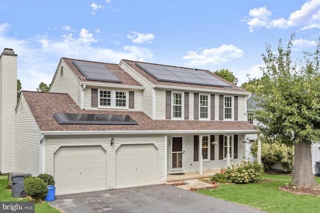 view of front of property with a porch, a garage, a front lawn, and solar panels