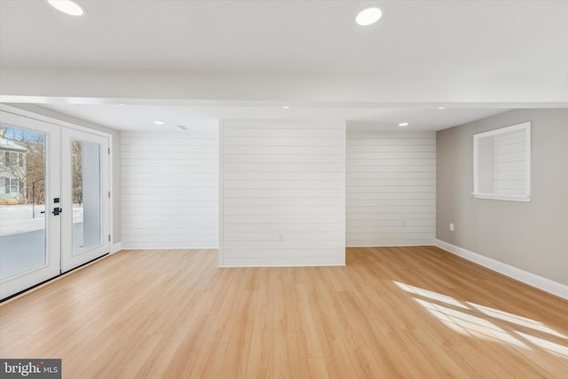 empty room featuring wood walls, light hardwood / wood-style flooring, and french doors