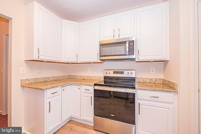 kitchen with light stone counters, white cabinets, and appliances with stainless steel finishes