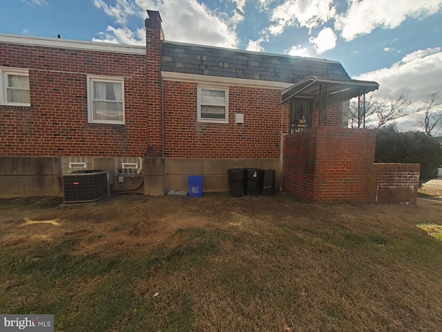 rear view of house with central AC and a lawn