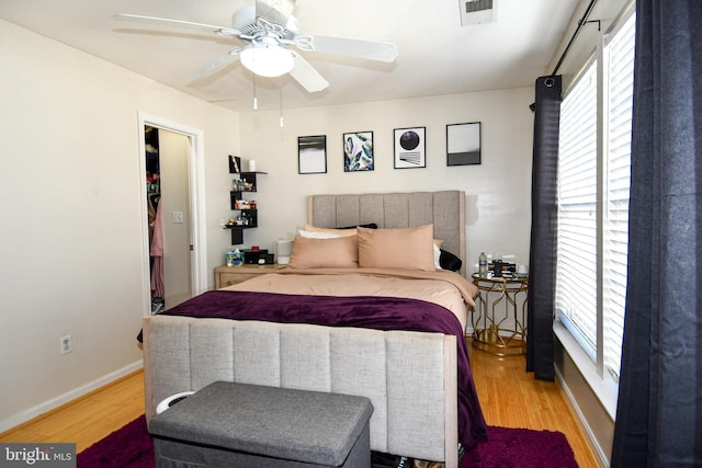 bedroom featuring hardwood / wood-style flooring, ceiling fan, and multiple windows